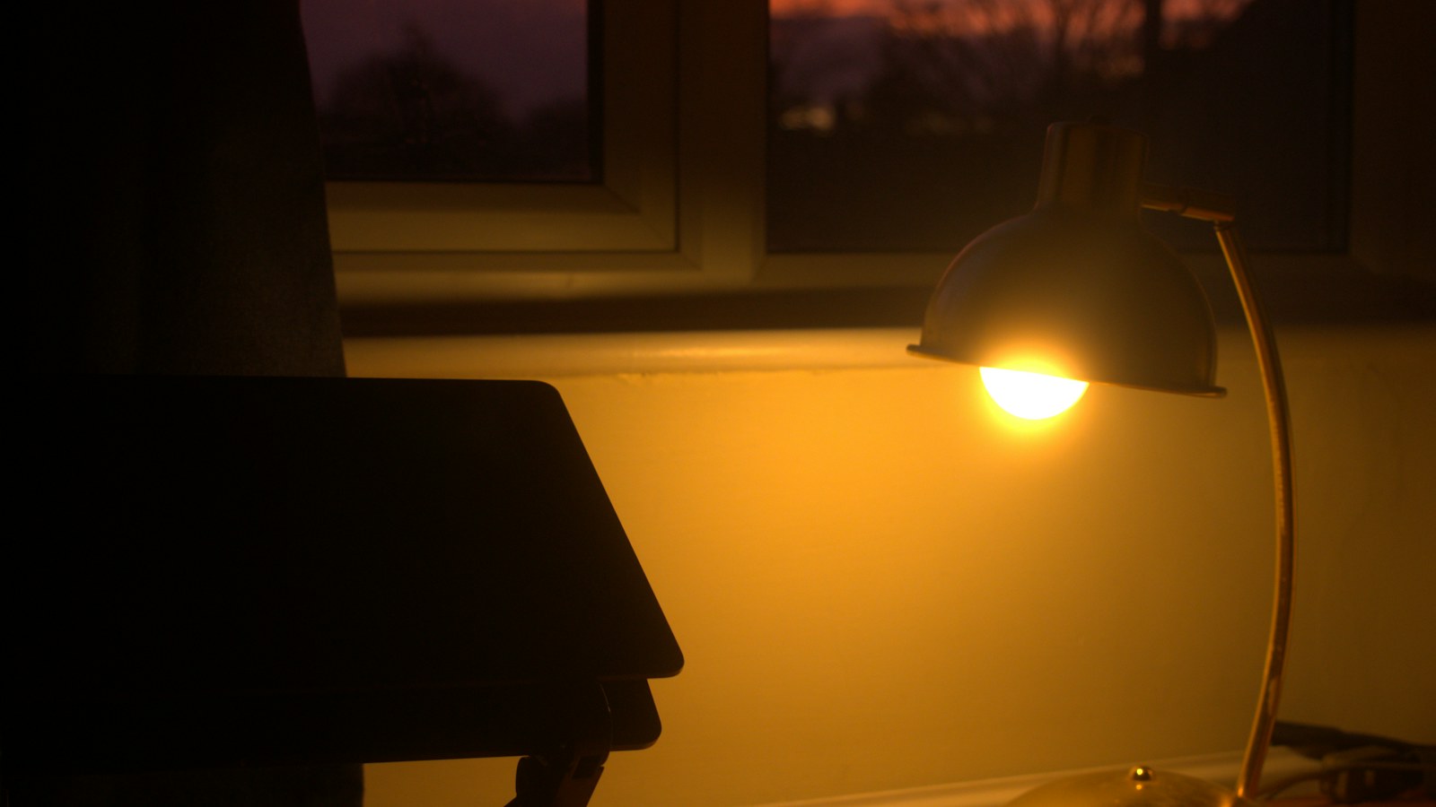 Une lampe de bureau allumée au crépuscule